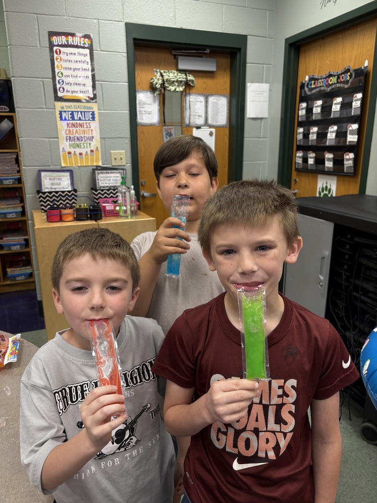Three boys, one in a gray shirt, another in a white shirt, and the third in a maroon shirt, holding green slushies.
