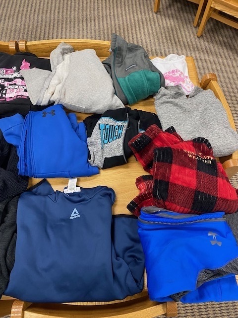 A wooden tray filled with various clothing items, including shirts, pants, and shorts in different colors and patterns.