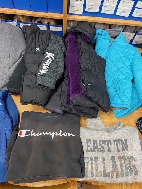 Various jackets in different colors and brands are on display. A wooden table holds a collection of jackets and sweatshirts.