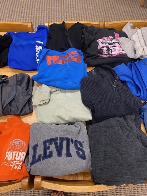 A table with multiple shirts and sweatshirts of various colors and brands displayed on it.