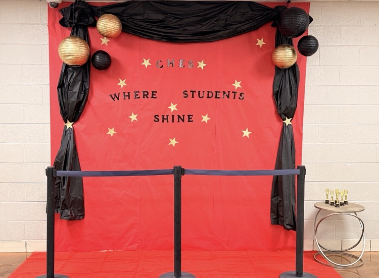 an image shows a red backdrop with black red text that reads “CHES” where students shine.