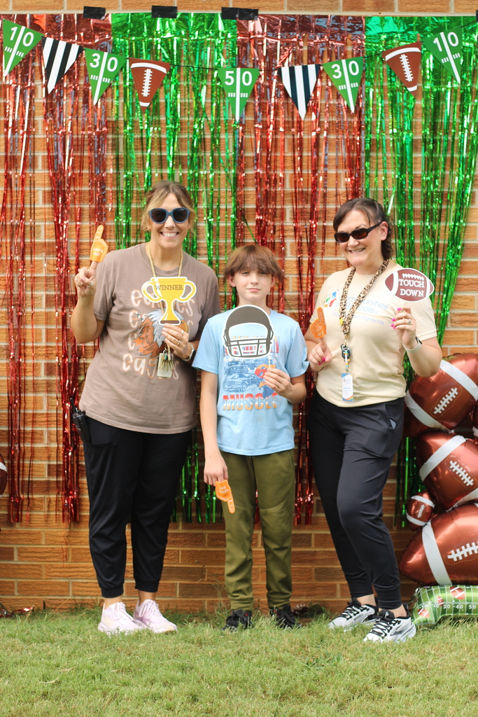 Three people, two women and a boy, pose for a photo in front of a decorated backdrop.