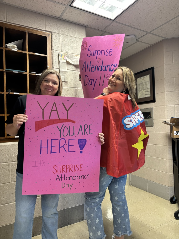 principals with surprise attendance day signs. 