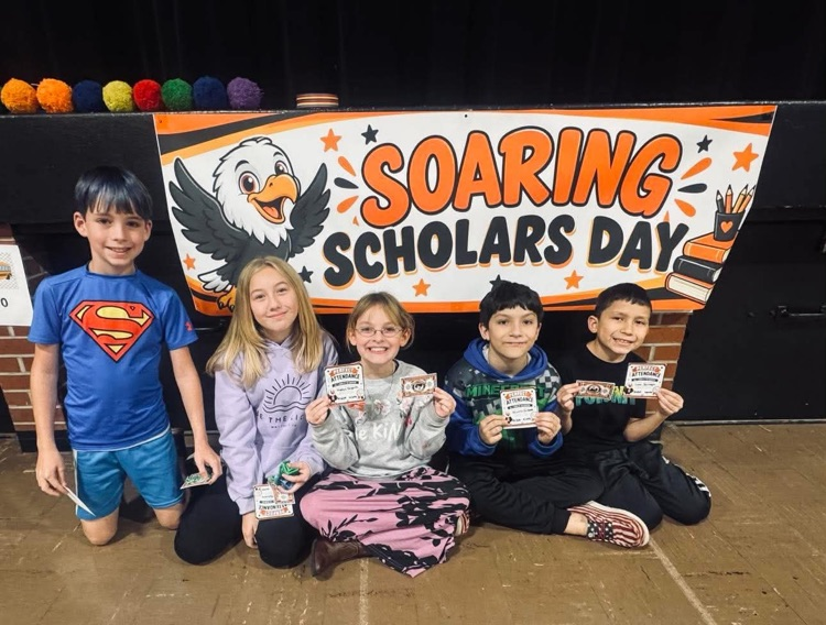 Five children, sitting and kneeling, hold certificates and smile in front of a banner.