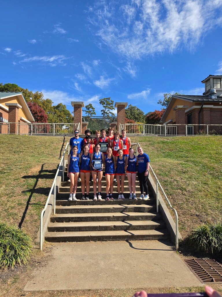 A group of people in blue uniforms standing on outdoor stairs with buildings in the background.
