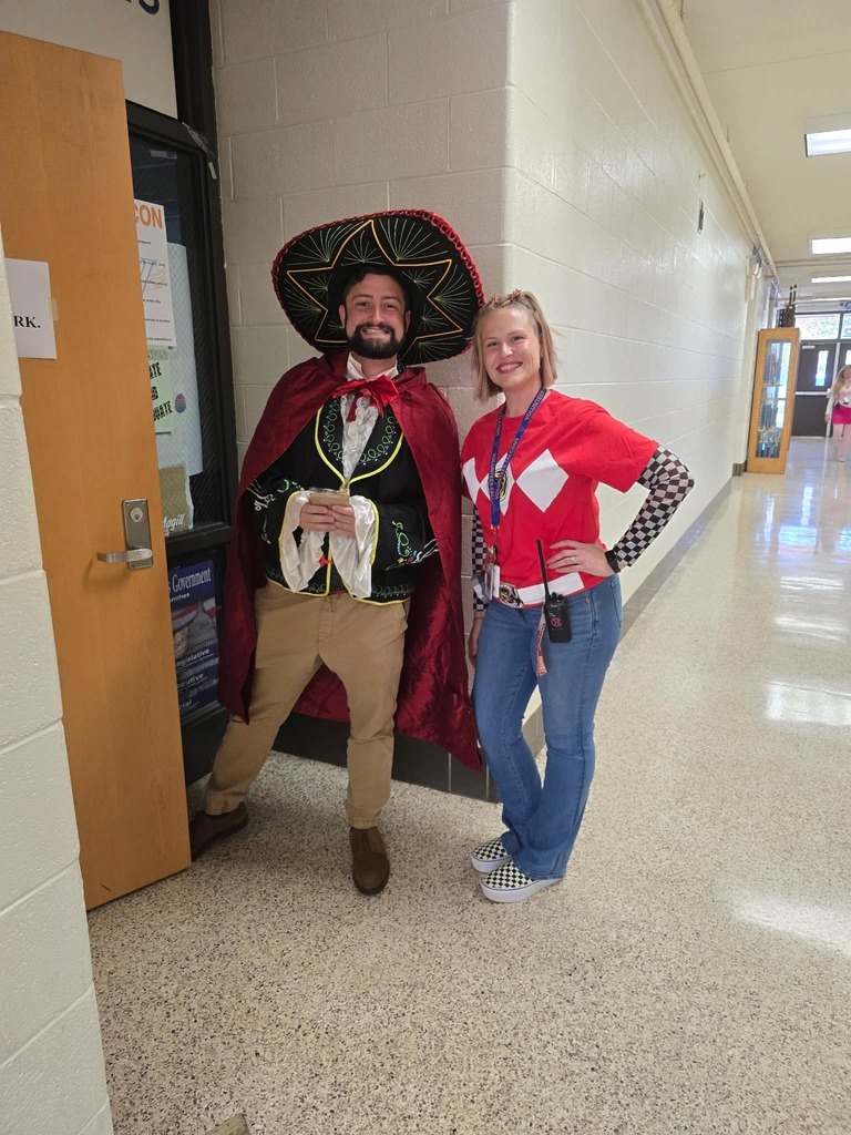 Person in costume next to a person in a red shirt with white stripes.
