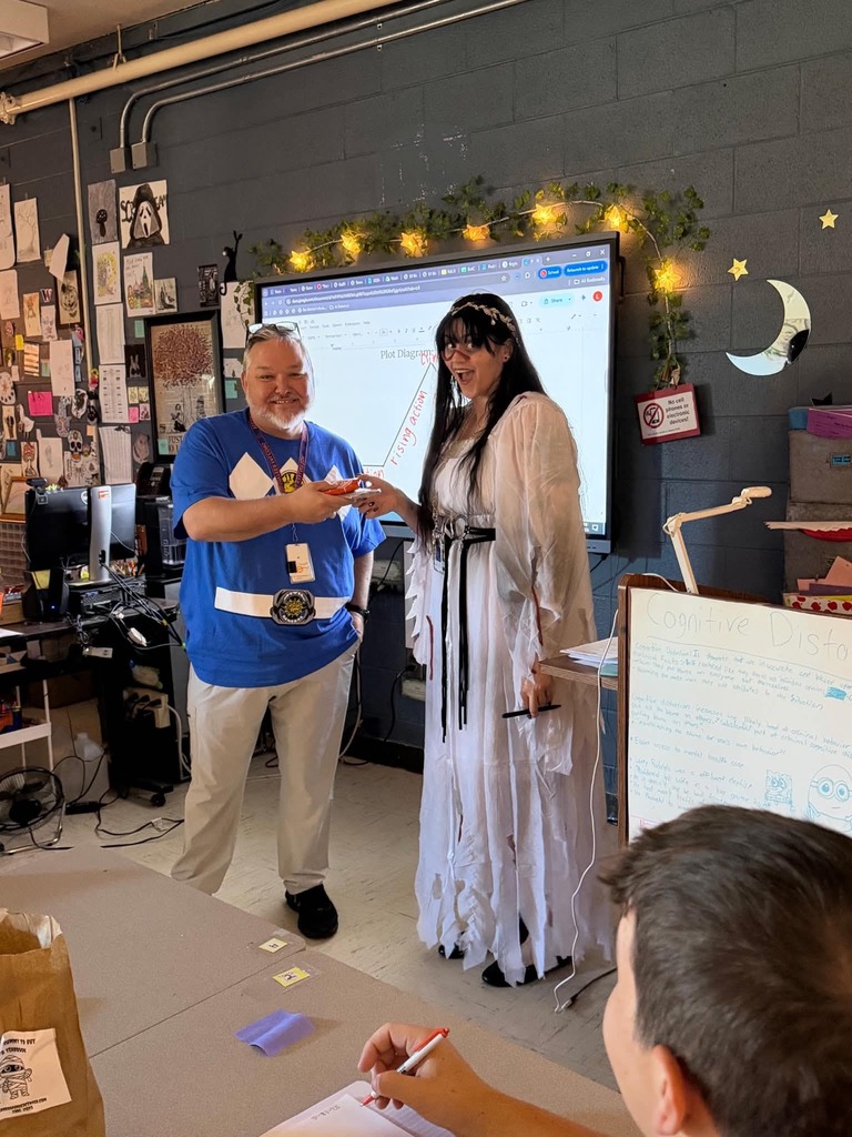 Two people in costumes in a classroom.