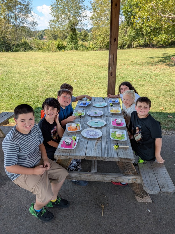 students at picnic table with cupcakes