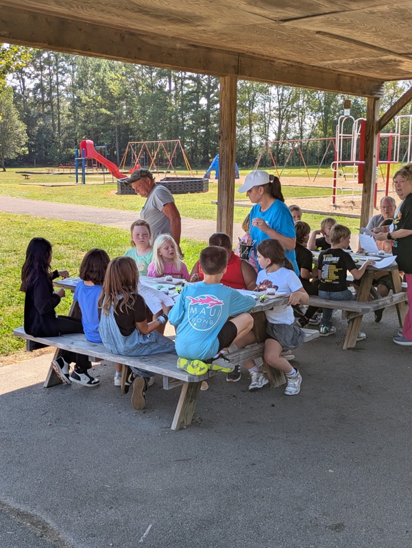 students at picnic table with cupcakes