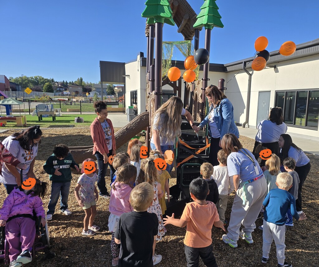 Preschool Playground Ribbon cutting - Ms. Hailee and Ms. Tami cutting the ribbon with students watching