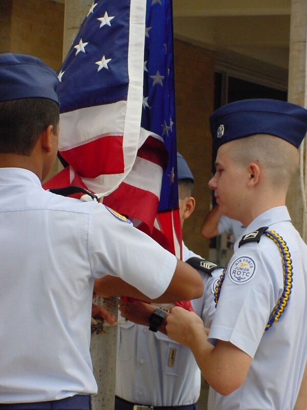 A photo of young men wearing Air Force blues uniforms while standing around an American flag.