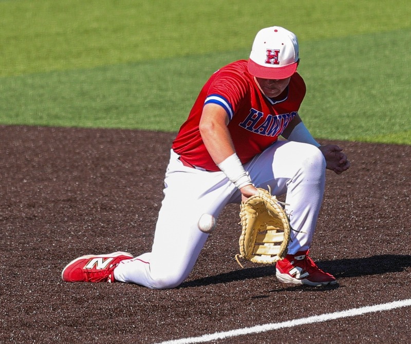 A baseball player in a Hays high school baseball uniform kneeling and catching a ball.