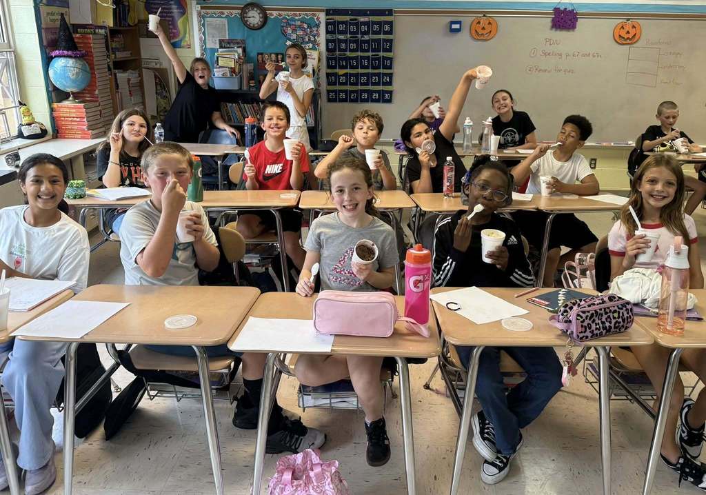 students holding ice cream at their desks after winning a competition