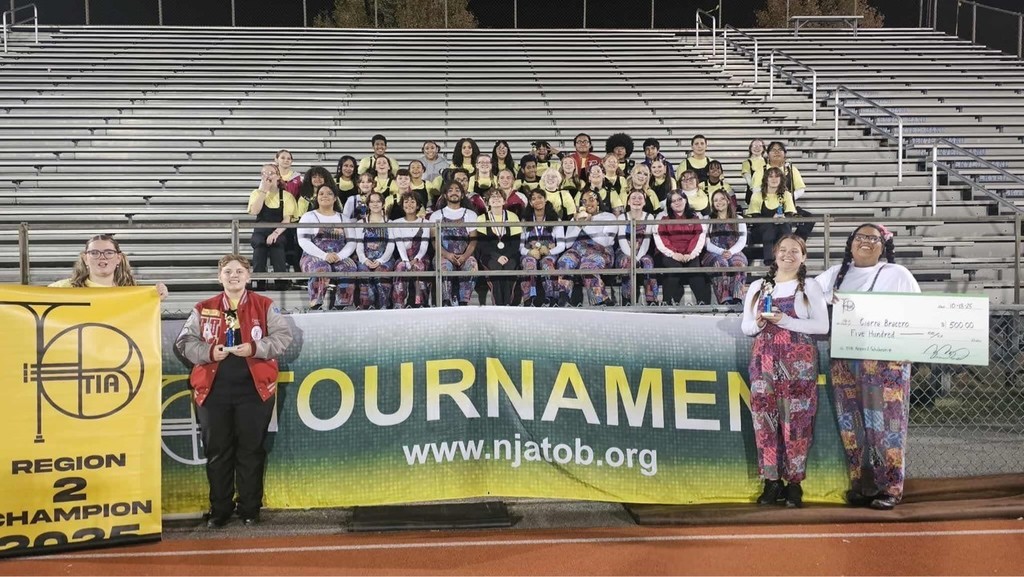 marching band posing with banner and check after placing first at a competition
