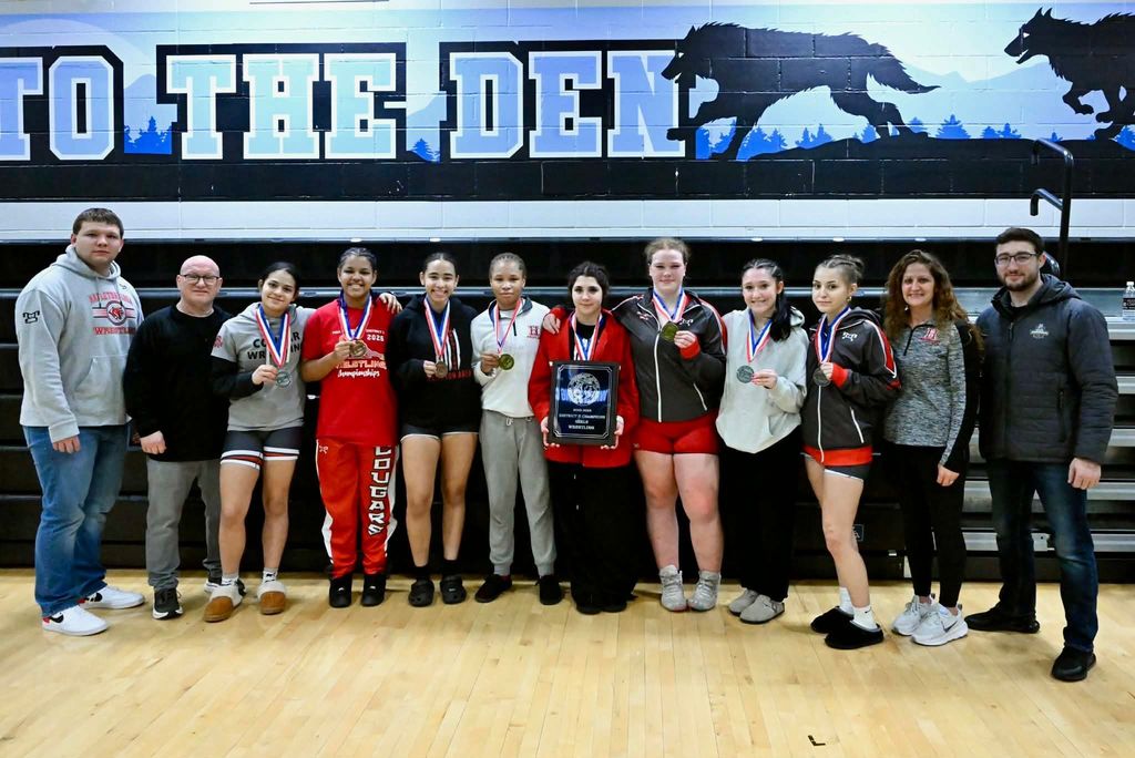girls wrestling team with medals and 1st place district plaque
