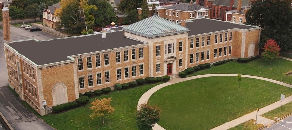 Aerial view of Health Sciences Charter School's little health location - at 1069 Delaware Avenue, showing the historic brick building, front lawn, and surrounding campus.