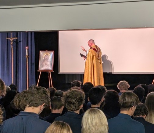 Fr. Brian blesses the Sacred Heart of Jesus image before being hung during the Enthronement ceremony