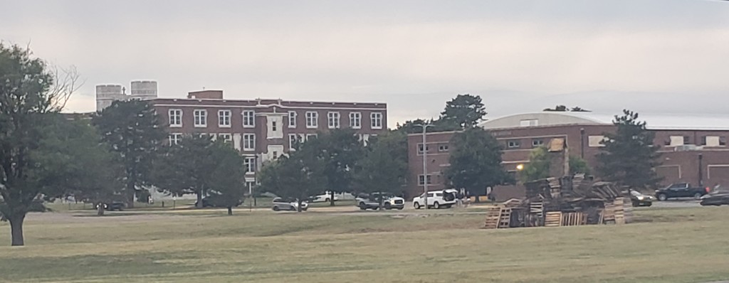 The wooden pallets are stacked for TMP-Marian's 2025 Bonfire with the school buildings in the background.