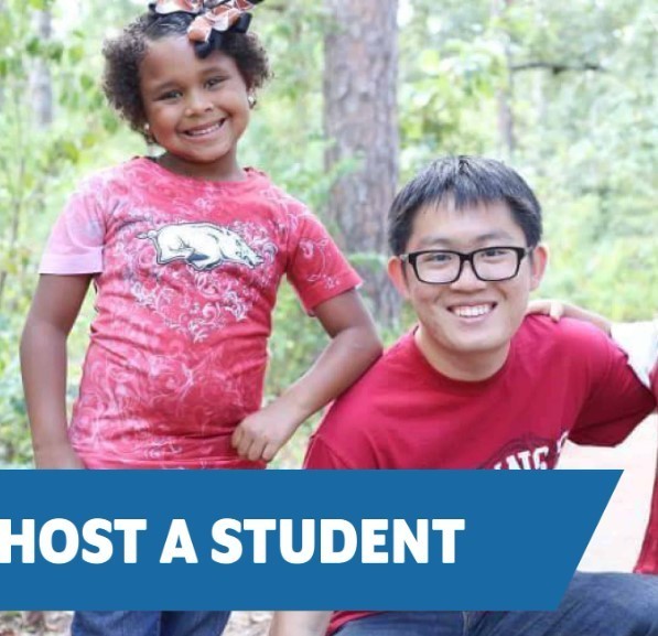 Girl and teenage boy in red t-shirts smiling with trees in the background
