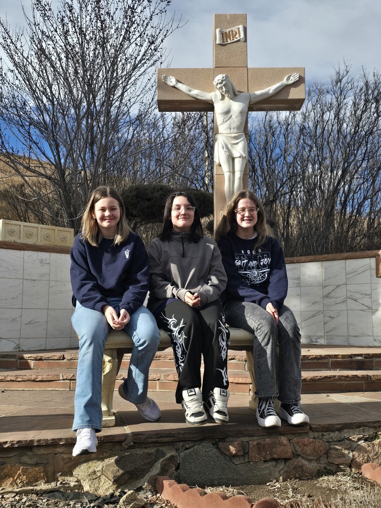 Students on the trail to the Mother Cabrini Shrine posing in front of a crucifix