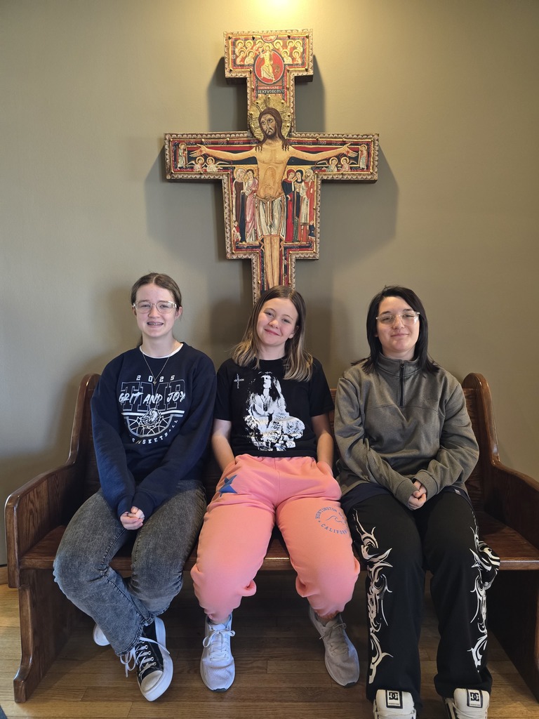 Students posing in front of an icon crucifix.