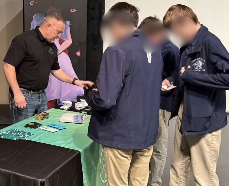 Students gather information at a table about cybersecurity