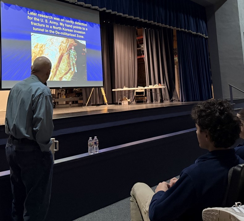 A man explains a picture to a group of students.
