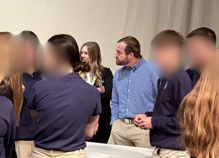 A man in a blue shirt listens to students questions on banking