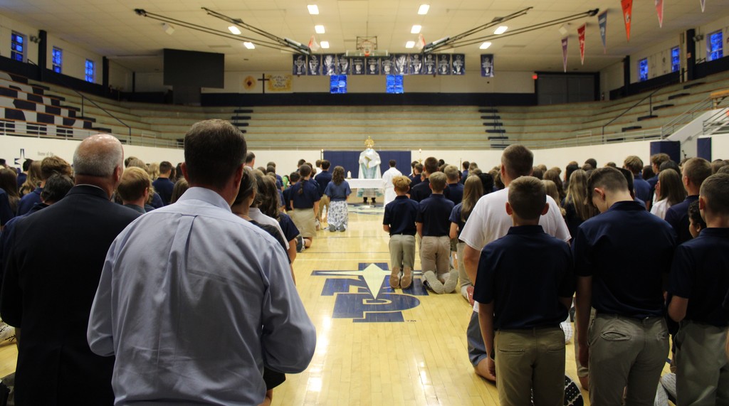 students kneeling on gym floor in adoration
