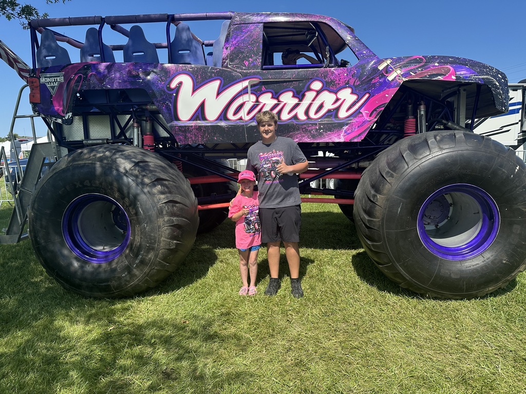 Boy and girl standing in front of purple and pink monster truck