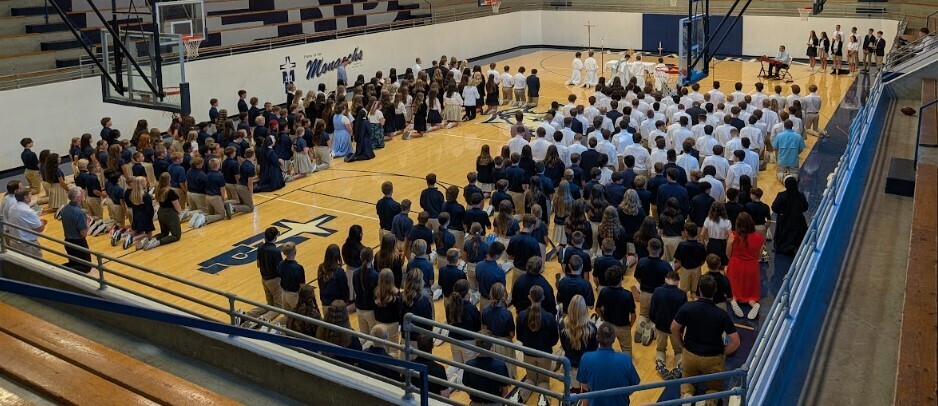 People adoring the Eucharist, kneeling on a gym floor