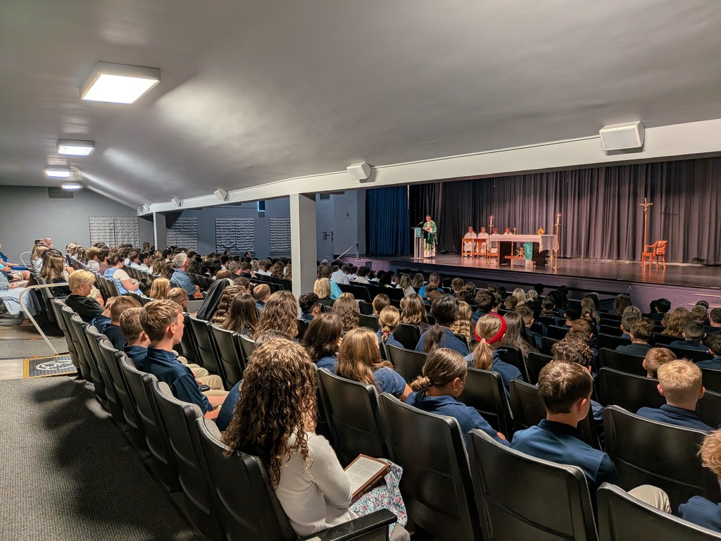 People seated at a school Mass in the auditorium
