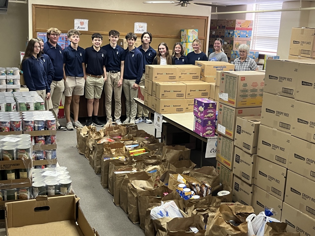 Students posing in front of boxed food stuffs.