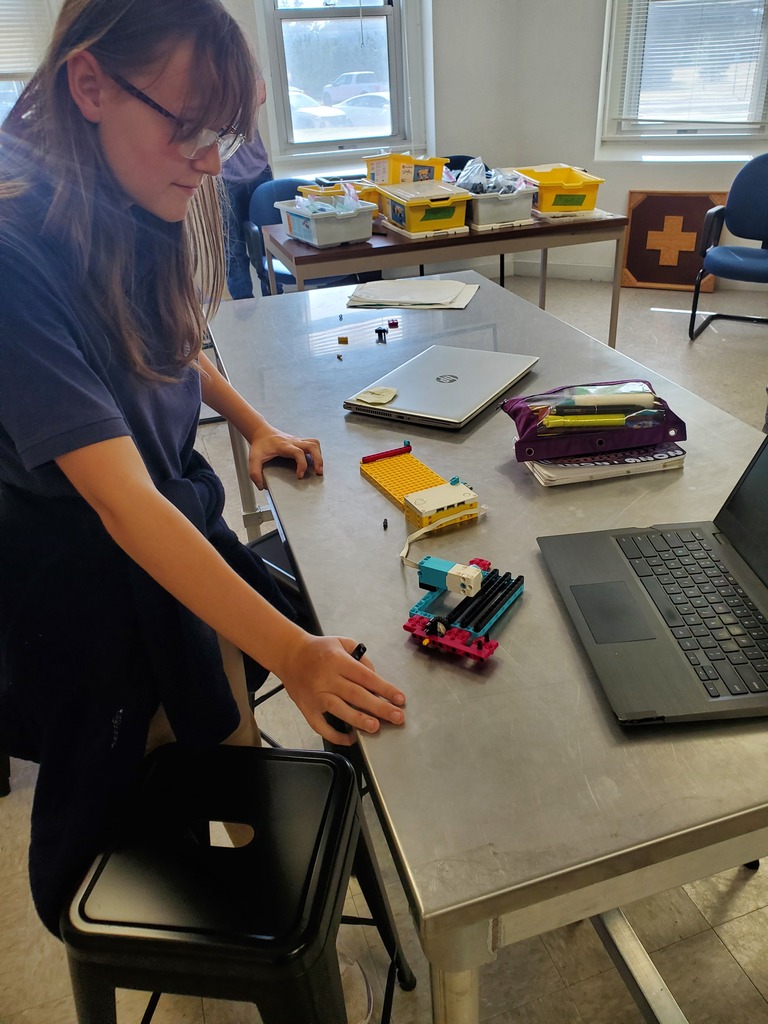 A student looks at her robot to consider her next step.