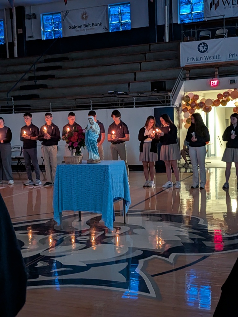 Students light a candle while praying a living rosary.