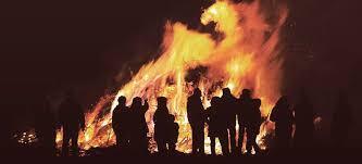 People silhouetted by a bonfire