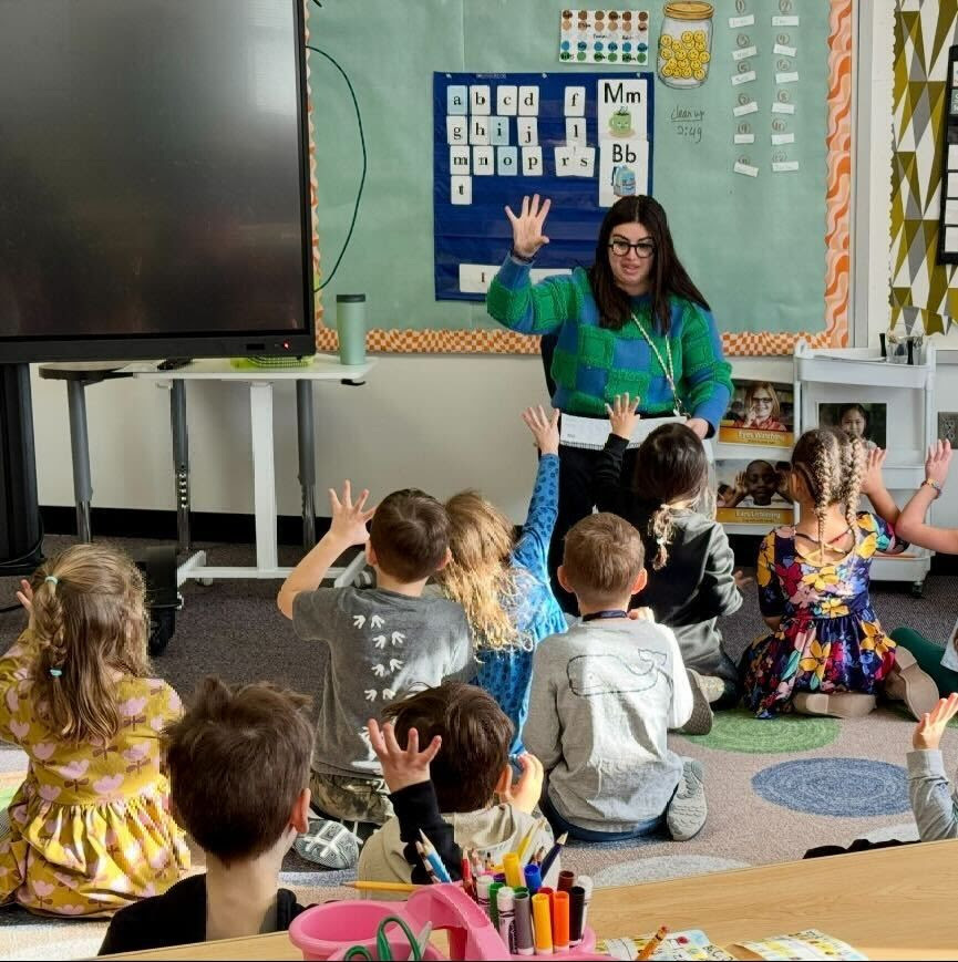 kindergarten teach and pre-kers raise hands as they practice phonics