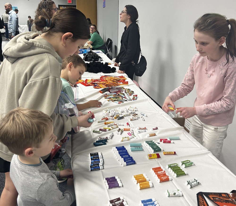 fifth grader helps children assemble care bags for people facing housing insecurity