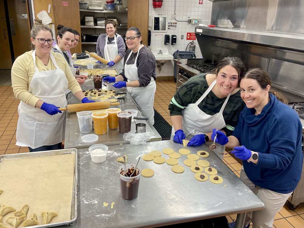 moms roll out, shape, and fill hamantaschen cookies in Heilicher kitchen