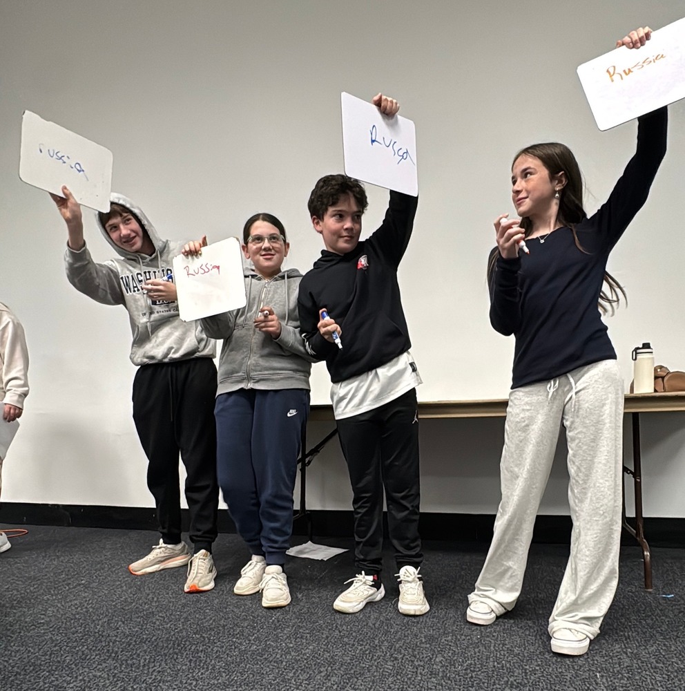 students raise white boards with their answers 