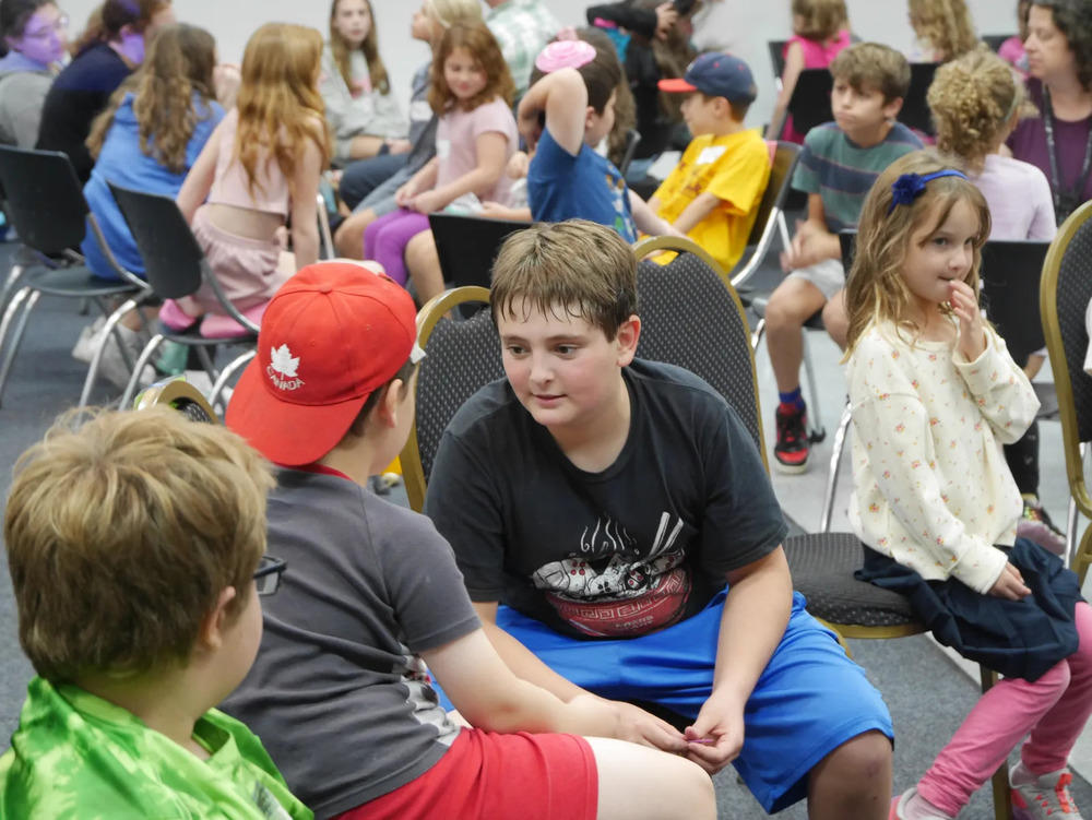 older student speaks with younger student and other kids around them also engage with one another