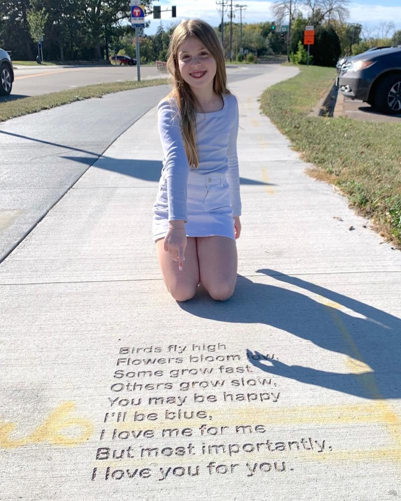 student with her poem engraved in sidewalk