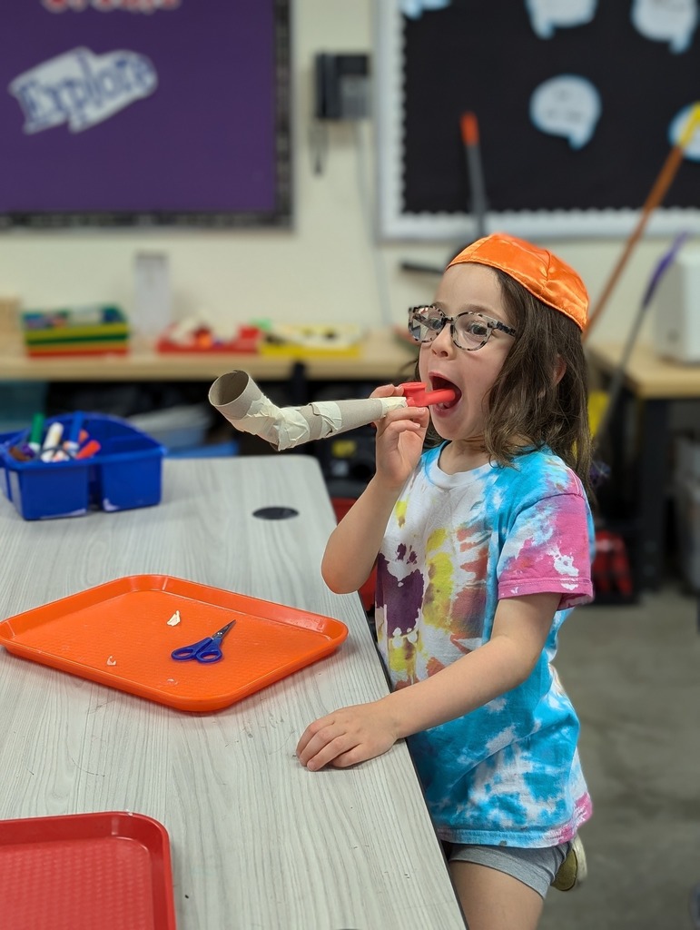 A student blowing a cardboard shofar