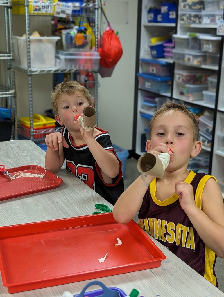Two kids blowing a cardboard shofar