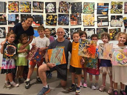 Owen Brown and kindergartners in front of and holding is abstract square paintings