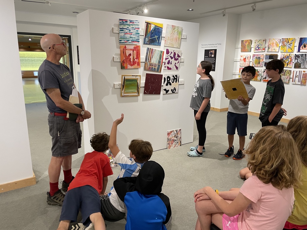 Students look at artwork on wall. one raises hand