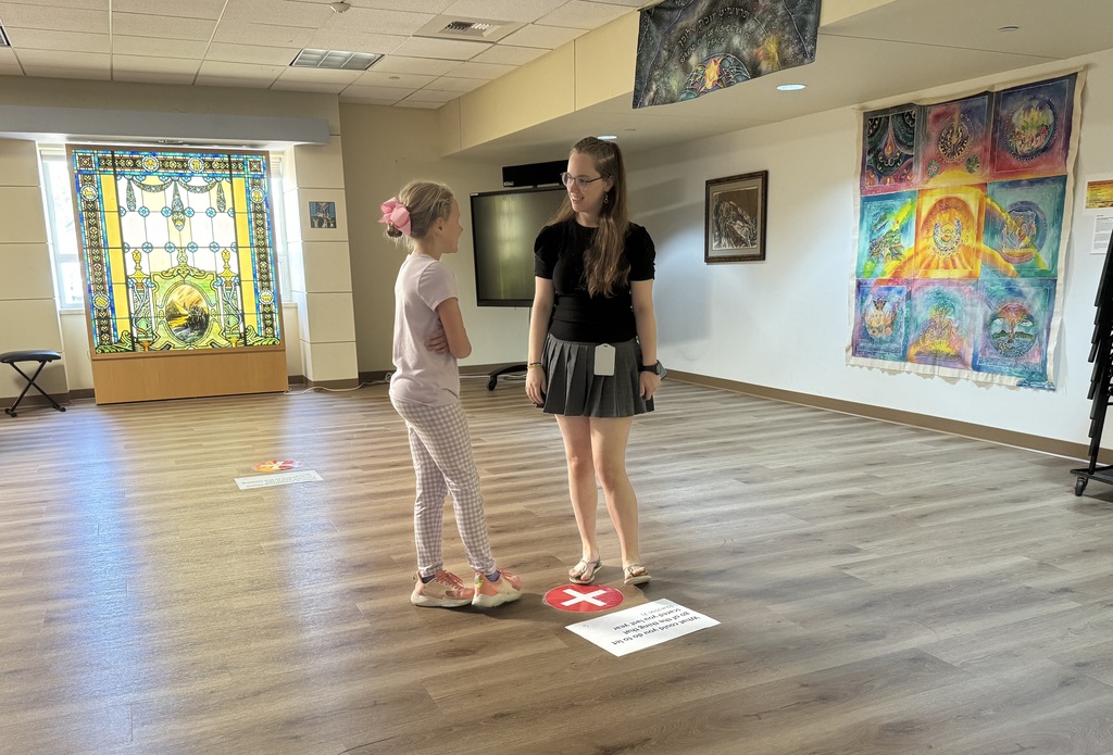 student and volunteer discuss question printed on paper on ground