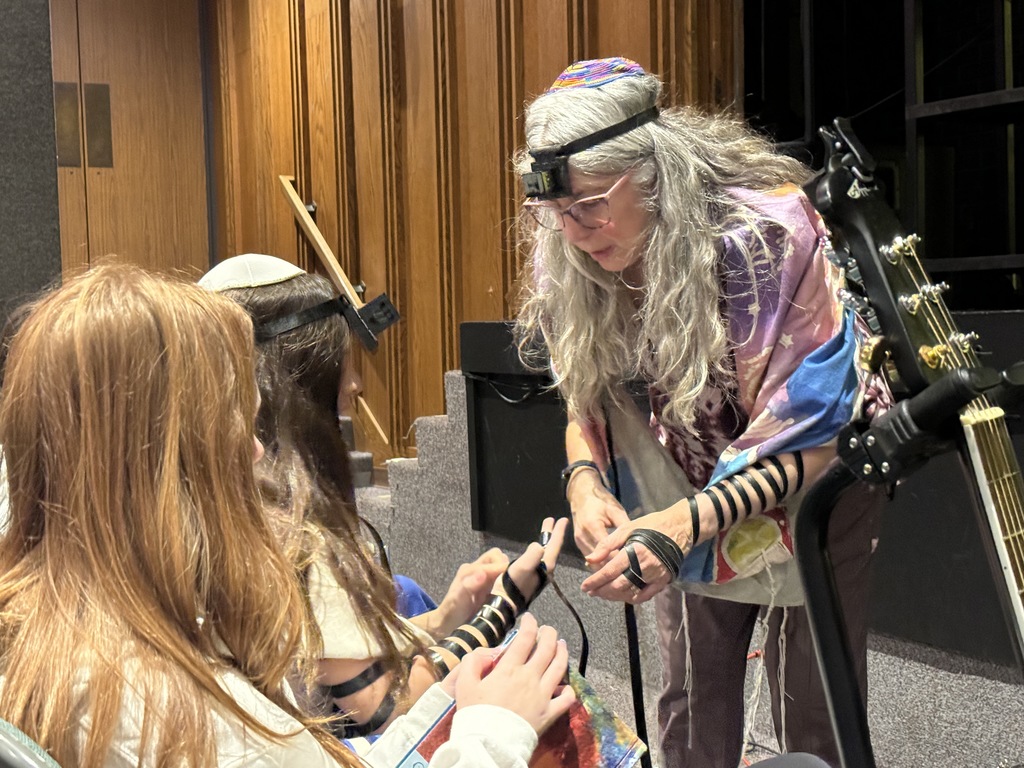 teacher helps bat mitzvah girl wrap t'filin