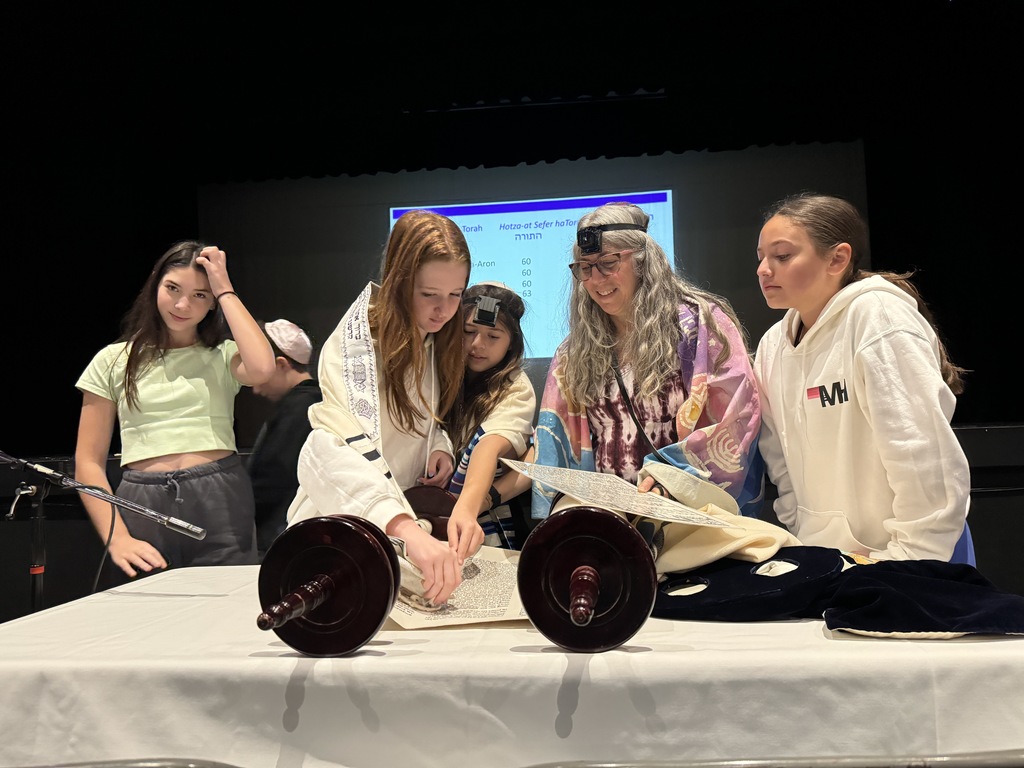 seventh-grade girl touches Torah with tzitzit, getting ready to have the aliyah