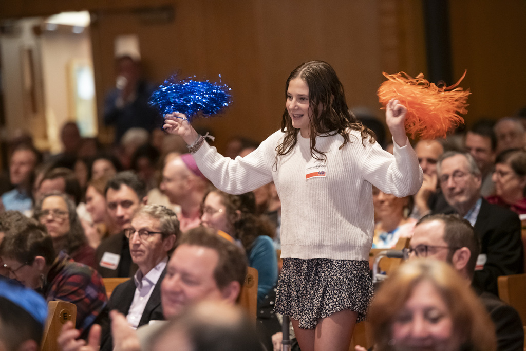eighth graders cheers on donors with blue and orange pom-poms